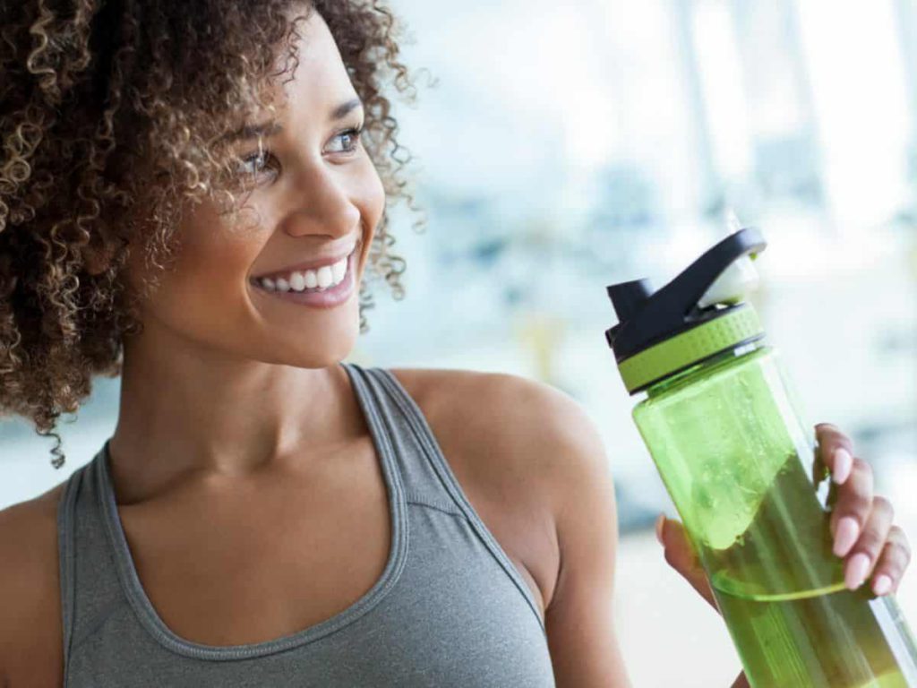 woman in gray tank top holding green water bottle